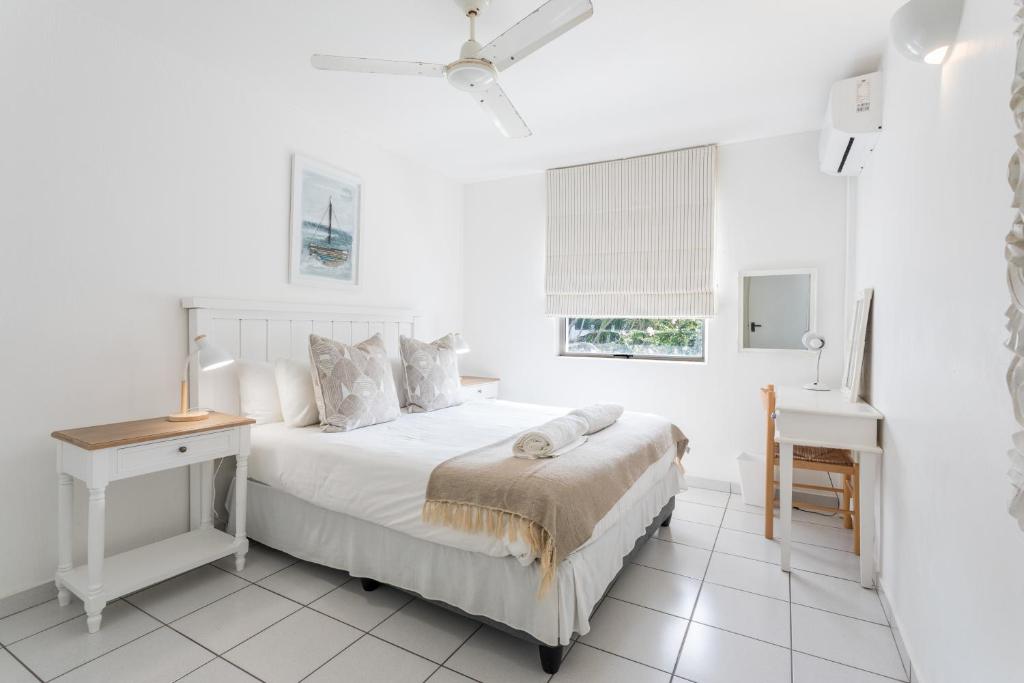 Main bedroom with a double bed, a ceiling fan and a desk at Ocean Blue
