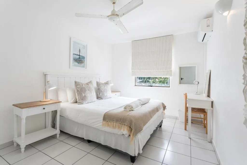 Main bedroom with a double bed, a ceiling fan and a desk at Ocean Blue