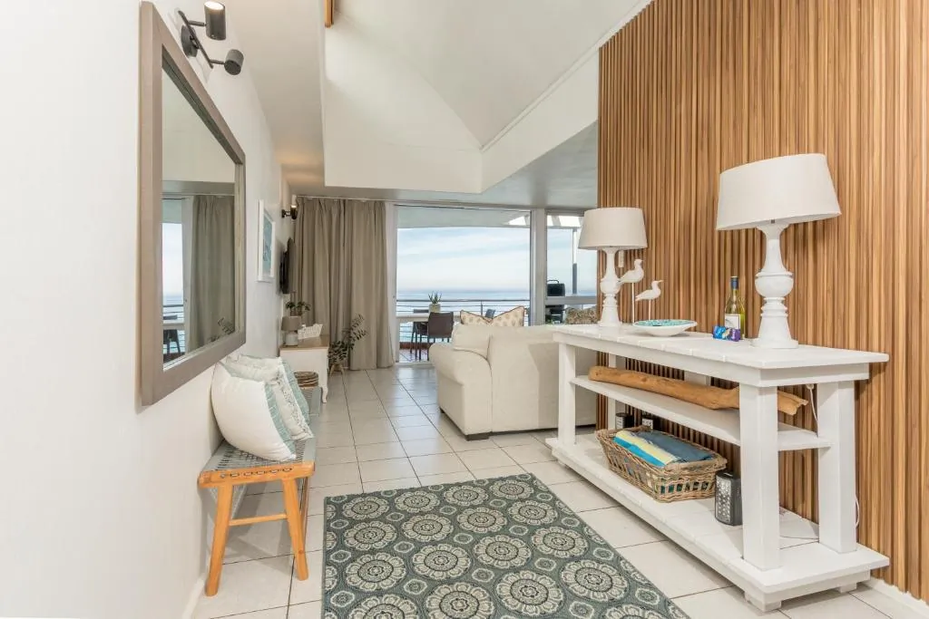 Entrance and living area with a console table and a lamp beside a sea view window at Ocean Blue