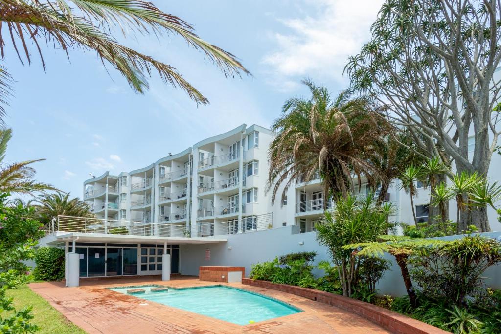 Pool on site with palm trees and the apartment building behind at Chaka's Cove