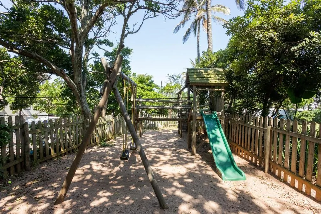 Children's playground with a slide and climbing frame among the trees at Chaka's Cove