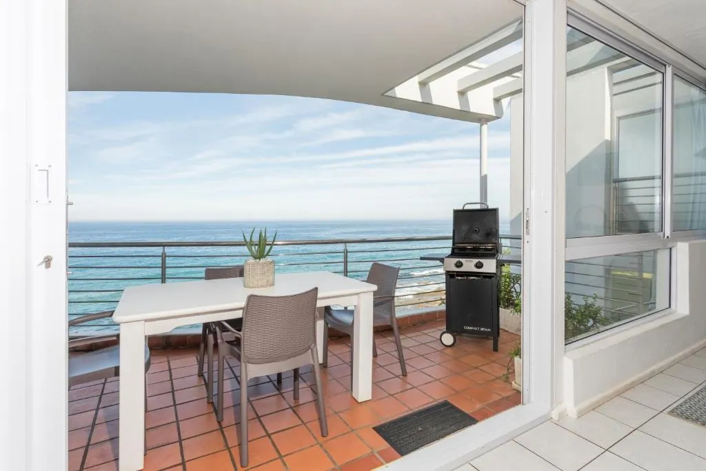 Balcony with a braai and dining set looking out over the ocean at Ocean Blue, a beachfront apartment at Chaka's Cove, Ballito