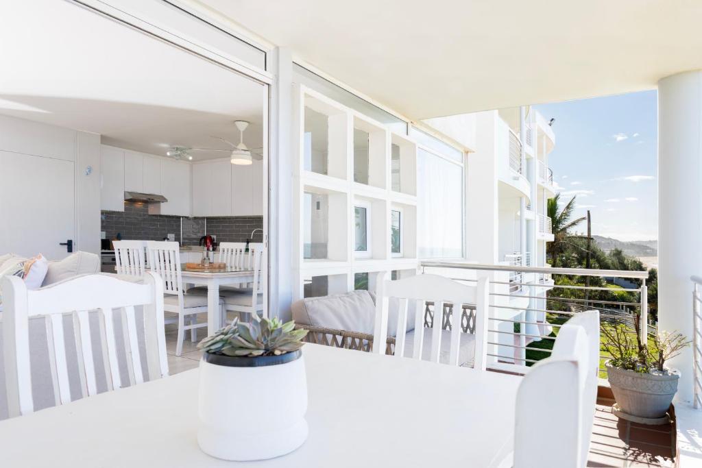 Bright open plan living area with white cabinetry opening onto the ocean view balcony at Ocean Pearl