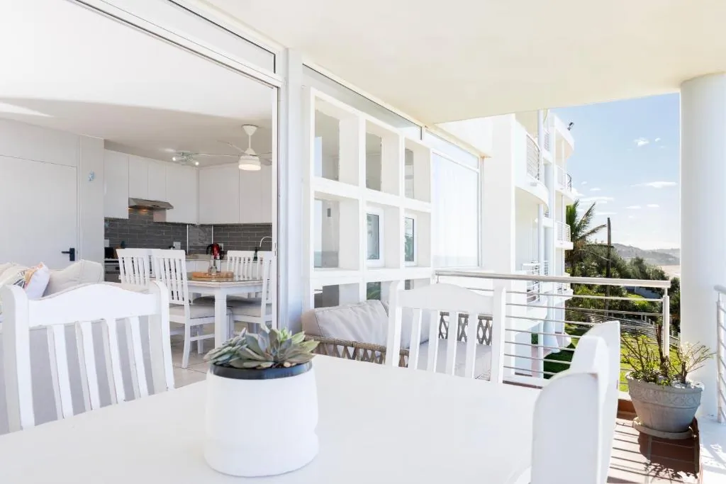 Bright open plan living area with white cabinetry opening onto the ocean view balcony at Ocean Pearl