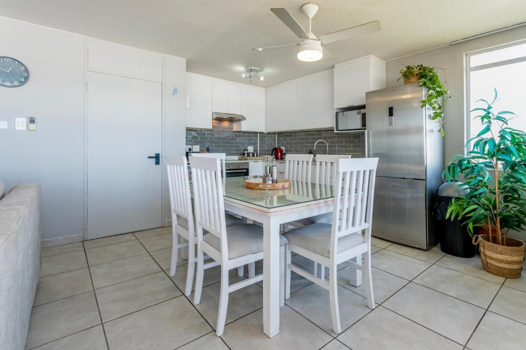 Kitchen and dining area with a white dining table and a full size fridge at Ocean Pearl