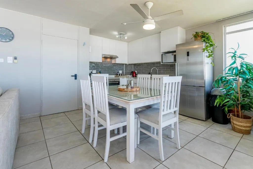 Kitchen and dining area with a white dining table and a full size fridge at Ocean Pearl