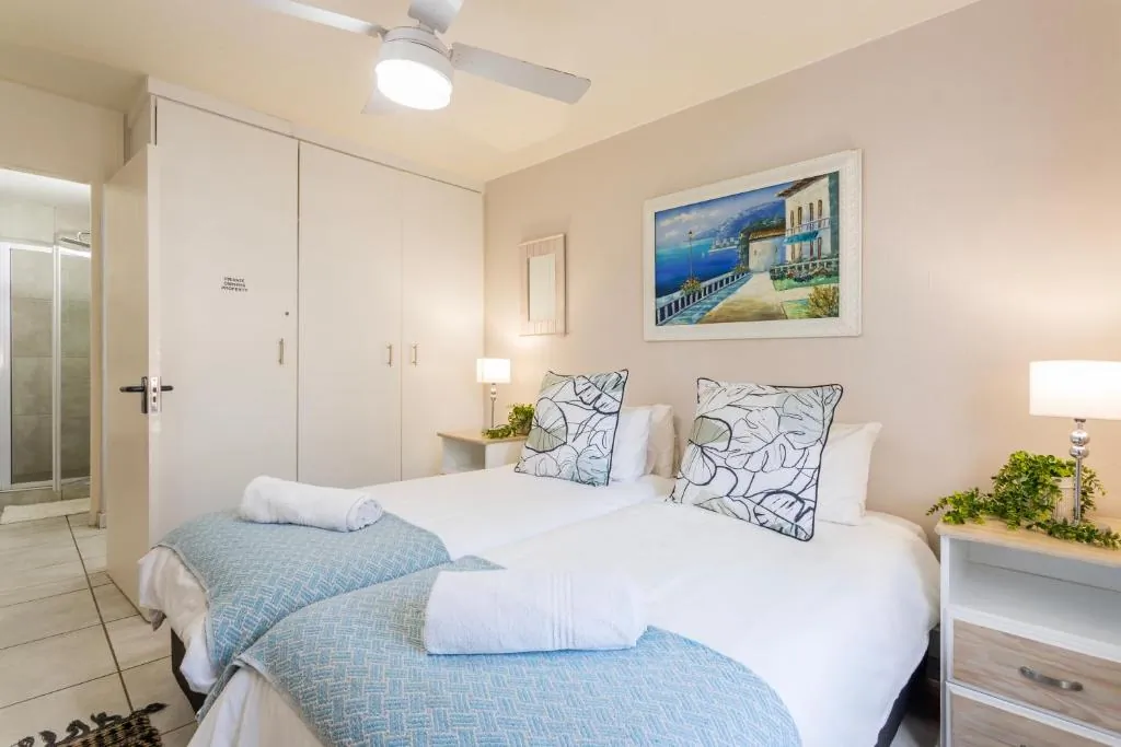 Second bedroom with two beds and coastal wall art at Ocean Pearl