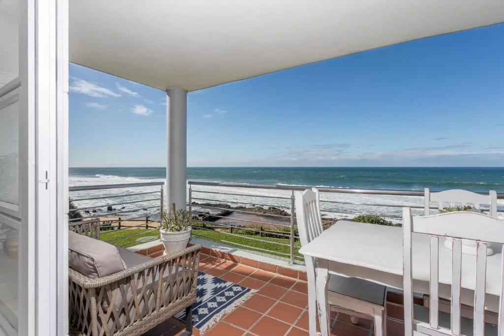 Covered balcony with a dining set looking out over the ocean at Ocean Pearl, a beachfront apartment at Chaka's Cove, Ballito